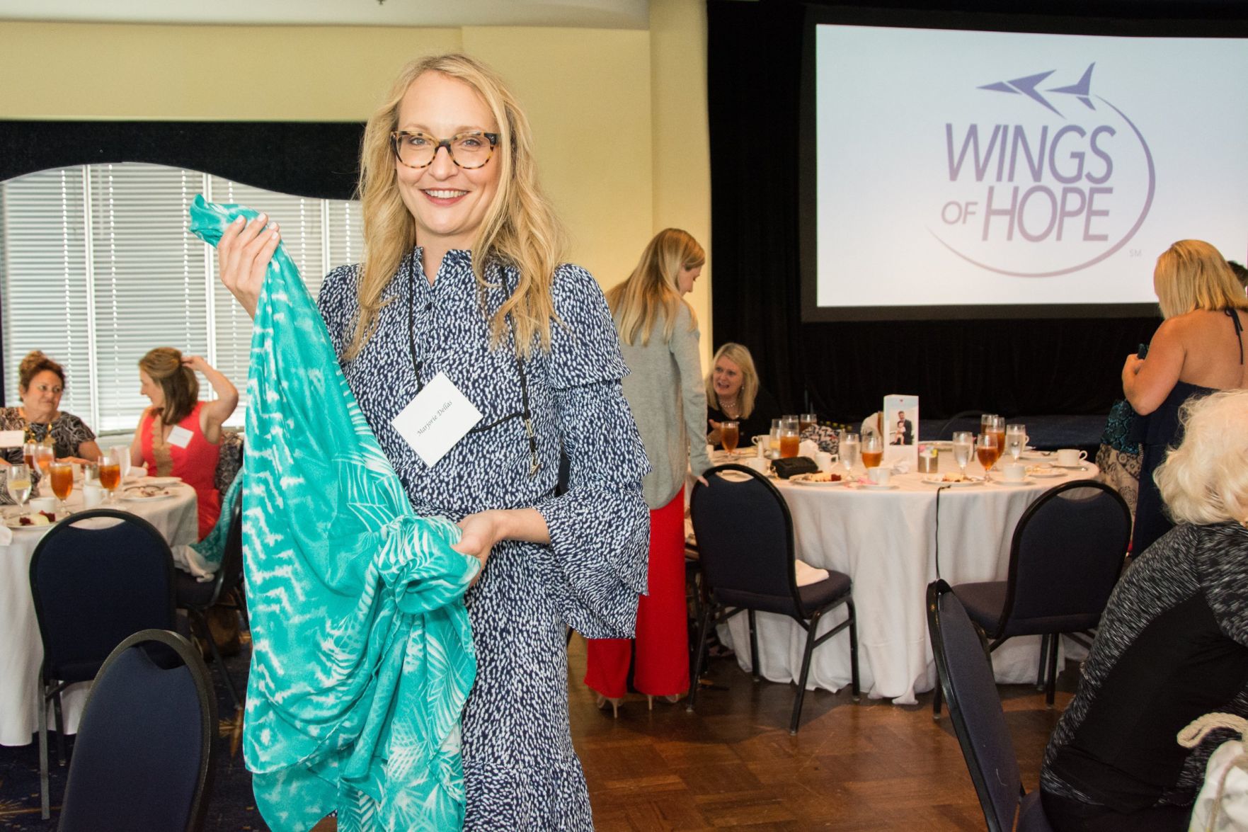 Marjorie Dellas shows off the scarf she selected as scarves have become a tradition of the luncheon.